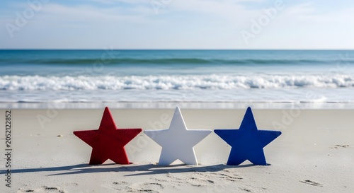 Labor Day Three decorative stars in red white and blue standing on sandy beach shore with ocean waves in background for patriotic holiday