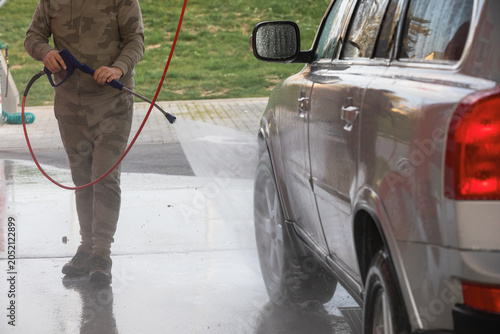 Man washing his car at an outdoor self-service  car wash station.
