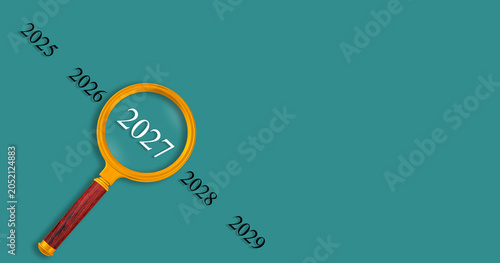 Magnifying glass focusing on 2027 year, business planning and future trends concept