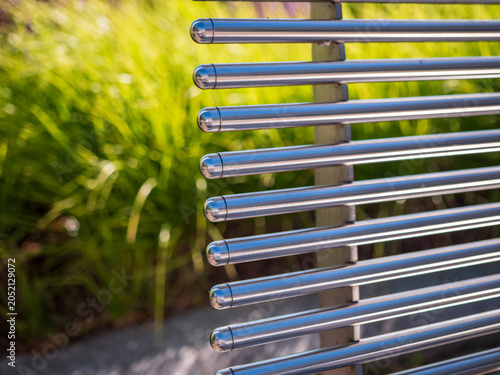 Quadro em tela Close-up of a modern stainless steel bench backrest with polished tubular bars and soft green background