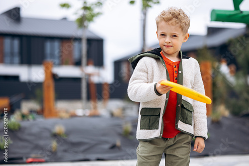 Obraz na plátne Young boy with blonde hair holding a yellow frisbee, enjoying outdoor playtime i