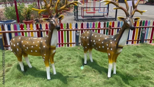 Decorative Deer Statues in Garden with Colorful Fence Background