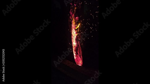 Tall fire log burning brightly in the dark
