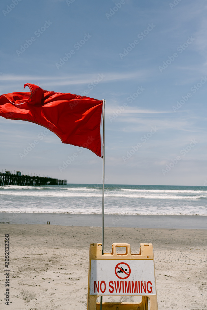 Obraz premium Red flag and no swimming sign on beach