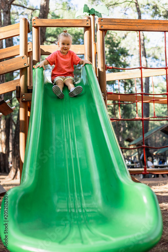 Smiling toddler at the top of a green playground slide