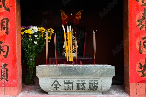 Fotografie Close up of stone altar with burning joss sticks and flowers at ancient na tcha