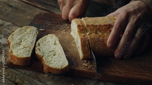 Hands slicing freshly baked loaf of ciabatta bread. Country bread, fresh pastry.