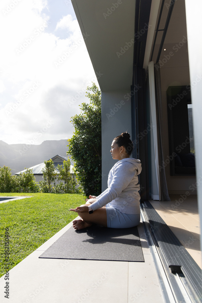 Fototapeta premium Yoga mat is resting on patio threshold and facing green lawn with distant mountain ridge
