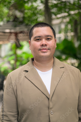 Confident plus size Isan Thai businessman in green garden vertical