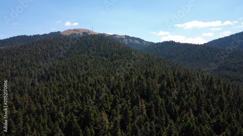 Remote high mountain with fir forest and antenna station on bare rocky summit