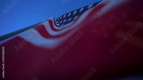 American flag billows majestically against a clear deep blue sky on a sunny day. Red and white stripes ripple while white stars on blue canton catch sunlight. Shallow depth of field creates soft.