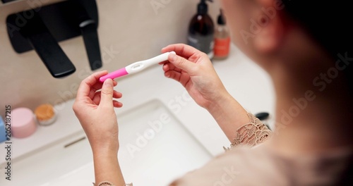 Fotografía Hands, pregnancy test and results in bathroom, home and check for fertility with screen in morning