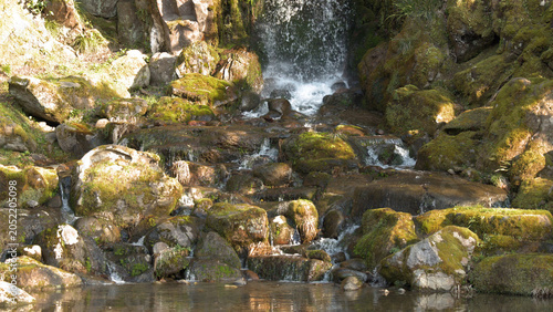 Foto Small Waterfall Cascading Over Mossy Rocks in a Japanese Garden