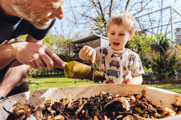Father and son inspecting worm farm in their garden
