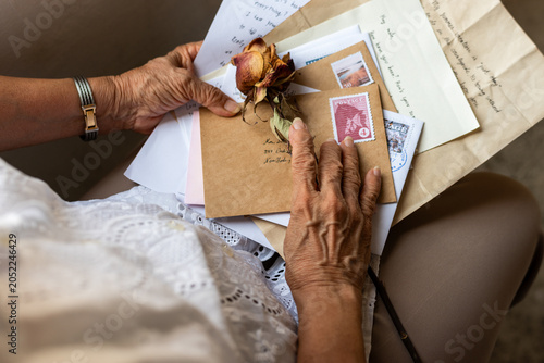 Obraz na płótnie Elderly person holding letters and dried rose, wearing a white lace top