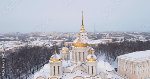 Cinematic aerial drone orbit shot of golden domes of Uspensky Cathedral in historic winter Vladimir