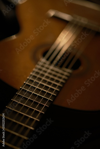 Cinematic view of a classical guitar with theatrical lighting. Elegant, artistic composition with ample dark space. Suitable for event branding, musical instrument catalogs, and cultural promotions.