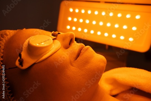 Relaxation during a skin treatment session under bright orange light