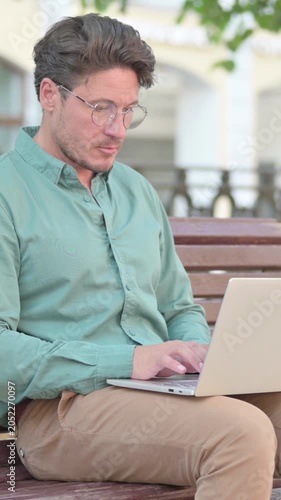 Man Working on Laptop on Bench Outdoor, vertical video