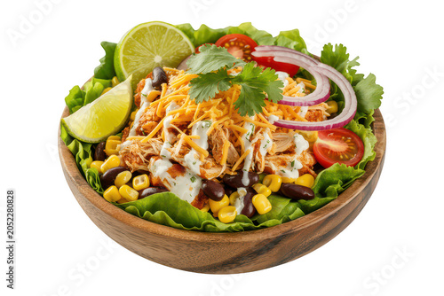 A wooden bowl filled with a chicken taco salad featuring black beans, corn, shredded cheese, red onion, cilantro, and lime on black background