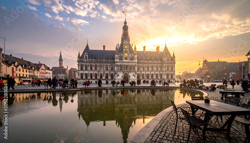 Historic European city hall at sunrise with reflections in water, architectural landmark and urban scenery