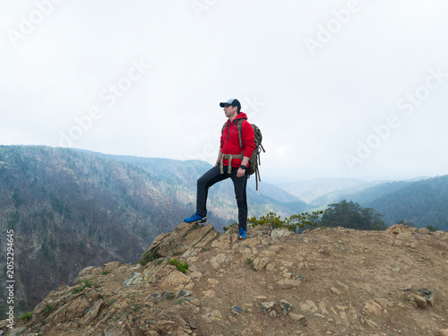 Eye level view of solo male hiker with backpack trekking on rugged mountain trail