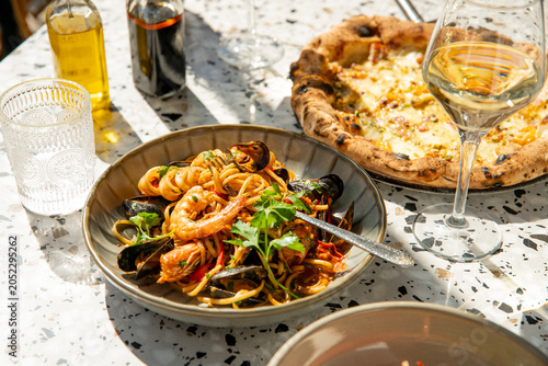 Delightful Seafood Pasta and Pizza Served With White Wine in a Bright Outdoor Setting