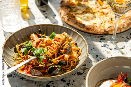 Vibrant Seafood Pasta Served Alongside a Rustic Pizza in a Sunny Outdoor Setting