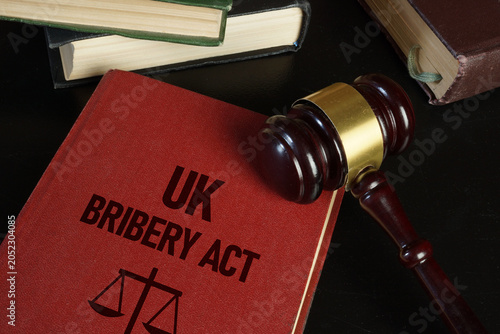 UK Bribery Act Legal Compliance Concept with Judge Gavel Law Books and Anti Corruption Legislation Reference on Dark Background
