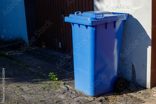 Foto Large blue plastic wheelie bin for paper and cardboard recycling standing outdoors