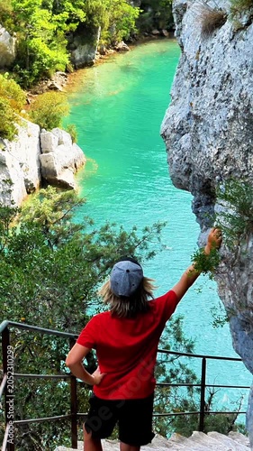 back view of a hiker looking down at the turquoise water of the gorges du verdon canyon in france