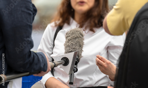 A news reporter conducting an interview with an individual for a media outlet, capturing professional journalism, communication, information gathering, and public reporting in action.