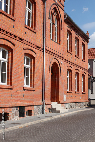 Fotografi Historic red brick building facade with arched entrance and traditional architectural details