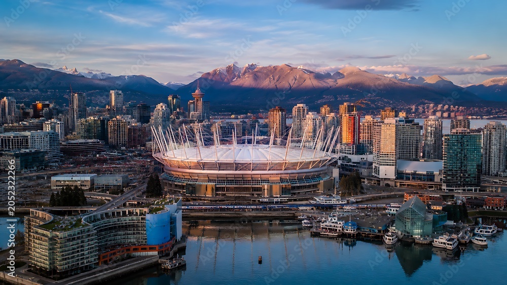 Obraz premium Aerial view of BC Place Stadium in Vancouver, Canada, at sunrise with mountains in the background.