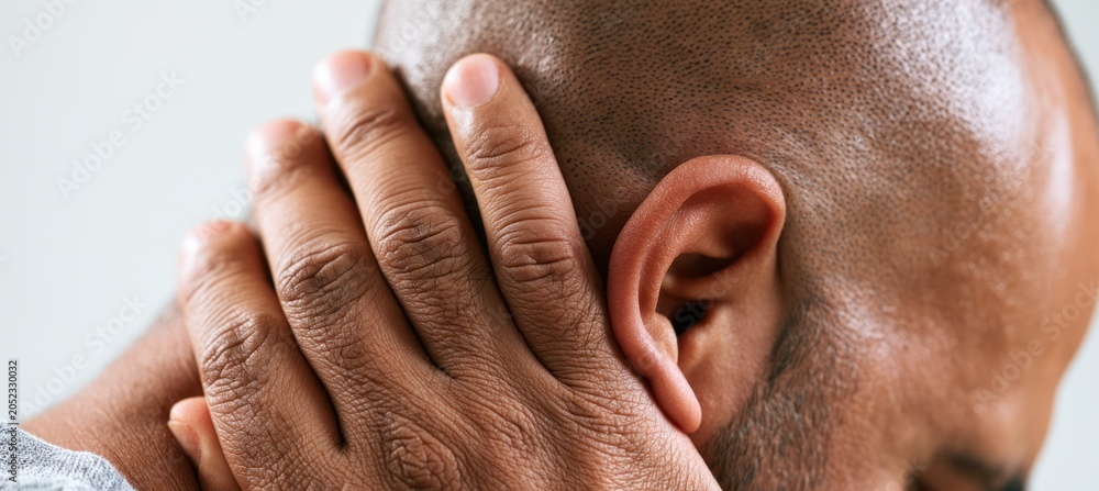 Naklejka premium Man experiencing neck pain, holding his neck with one hand