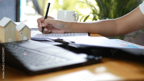 Fotografie Business professional reviewing financial documents and real estate investment reports at office desk with laptop and model houses