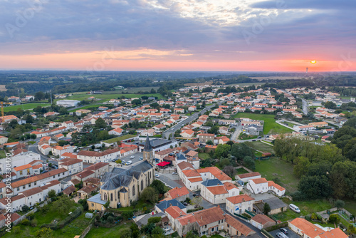 Aerial View of Village Church and Rooftops at Sunset Over Countryside Town, Mache, France