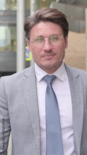 Close up of Middle Aged Businessman Walking towards Camera in Street, vertical video