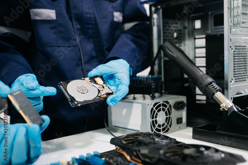 Technicians repairing computer hardware, testing components and upgrading PC systems. Technology service, electronics engineering and IT support concept.