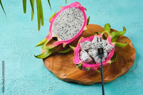Cubed pitahaya or dragon fruit pulp in a bowl made of its peel on a wooden board on a turquoise concrete background. Exotic fruits. Fruits from around the world.