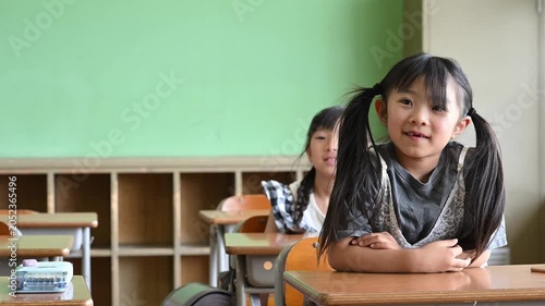 教室で笑顔で元気に手を挙げる女子小学生