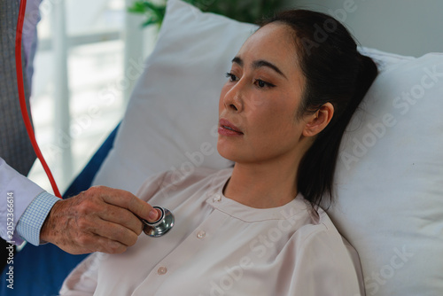 Billede på lærred Doctor performing a health check on an Asian female patient with a stethoscope,