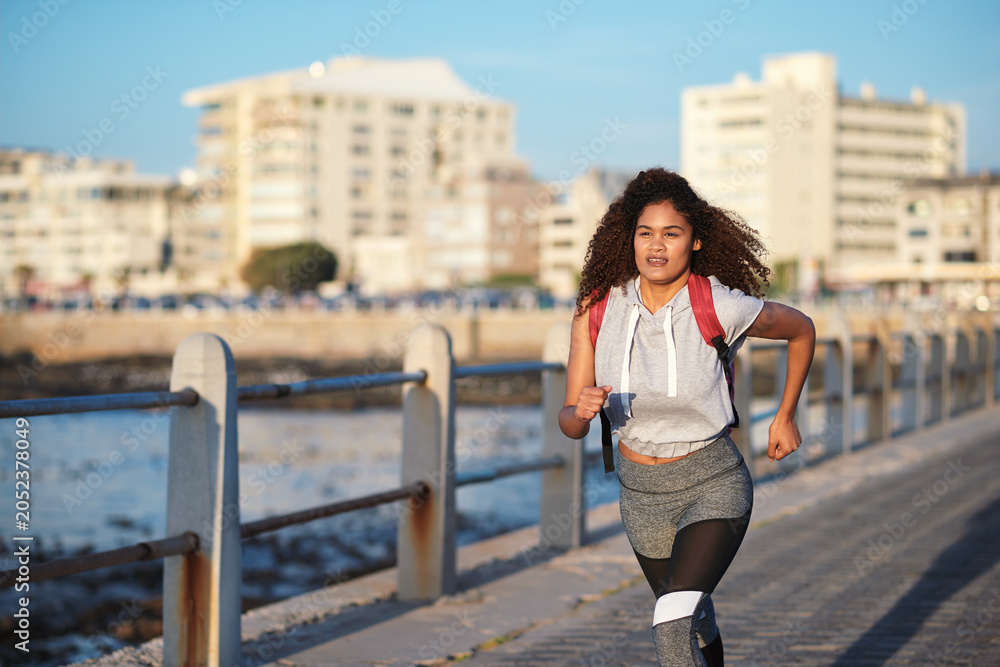 Naklejka premium Fitness, running or woman with exercise on boardwalk, endurance training or cardio routine for health. Promenade, commitment or athlete with distance challenge for wellness, morning workout or jog