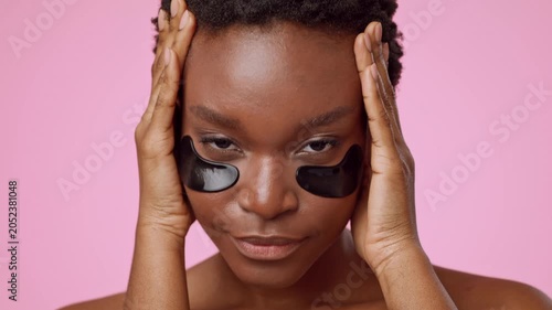 Focused Young Black Woman Applying Under Eye Patches As Part Of Skincare Routine At Home. Taking Care Of Skin While Relaxing In A Comfortable Indoor Setting. Self-care Concept