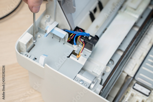 Hand Using Screwdriver Repairing Inkjet Printer Interior With Exposed Wires And Cables