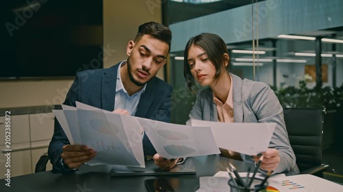 Focused Professionals, Male And Female, Analyzing Documents Together At Office Space, Engaged In Discussion. Capturing Elements Of Collaboration And Teamwork In A Modern Business Environment.