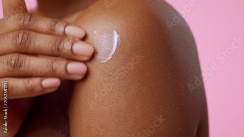 Focused Black Female Hand Applying Moisturizer On Smooth Skin Of Shoulder, In Home Setting For Self-care Routine. Emphasizing Importance Of Daily Skincare And Beauty Regimen, Wellness Concept