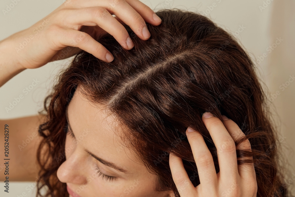 Fototapeta premium Close Up of Woman Examining Her Brown Curly Hair and Scalp with Hands - Hair Care and Texture Concept