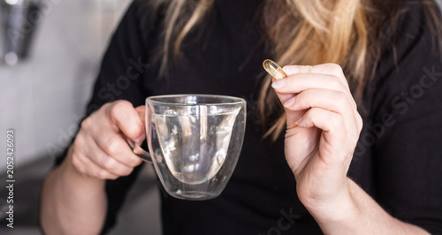 Schilderij op canvas A woman drinks clean water from a cup, relaxed in a casual, homely setting
