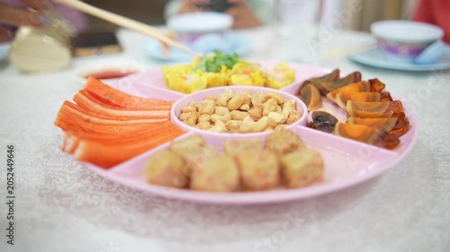 4K Close-up of hand using chopsticks to pick up century egg from colorful Chinese appetizer platter on banquet table, Traditional party catering festive dining and asian food concept.